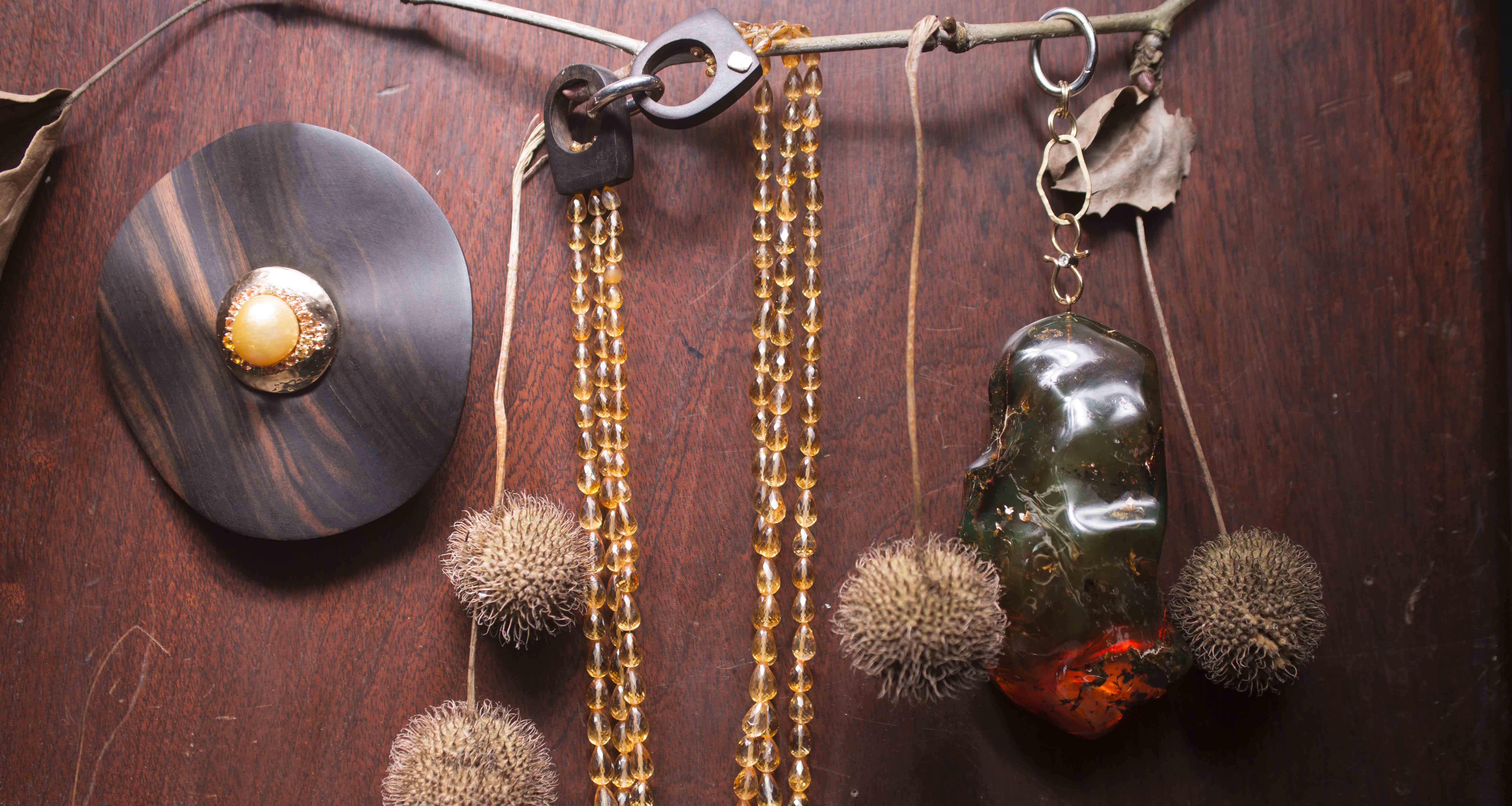 Collana di quarzo citrino ed ebano. Parte centrale in ebano con anello estraibile in oro giallo martellato con perla australiana, zaffiri gialli e arancio. Ciondolo in ambra verde.