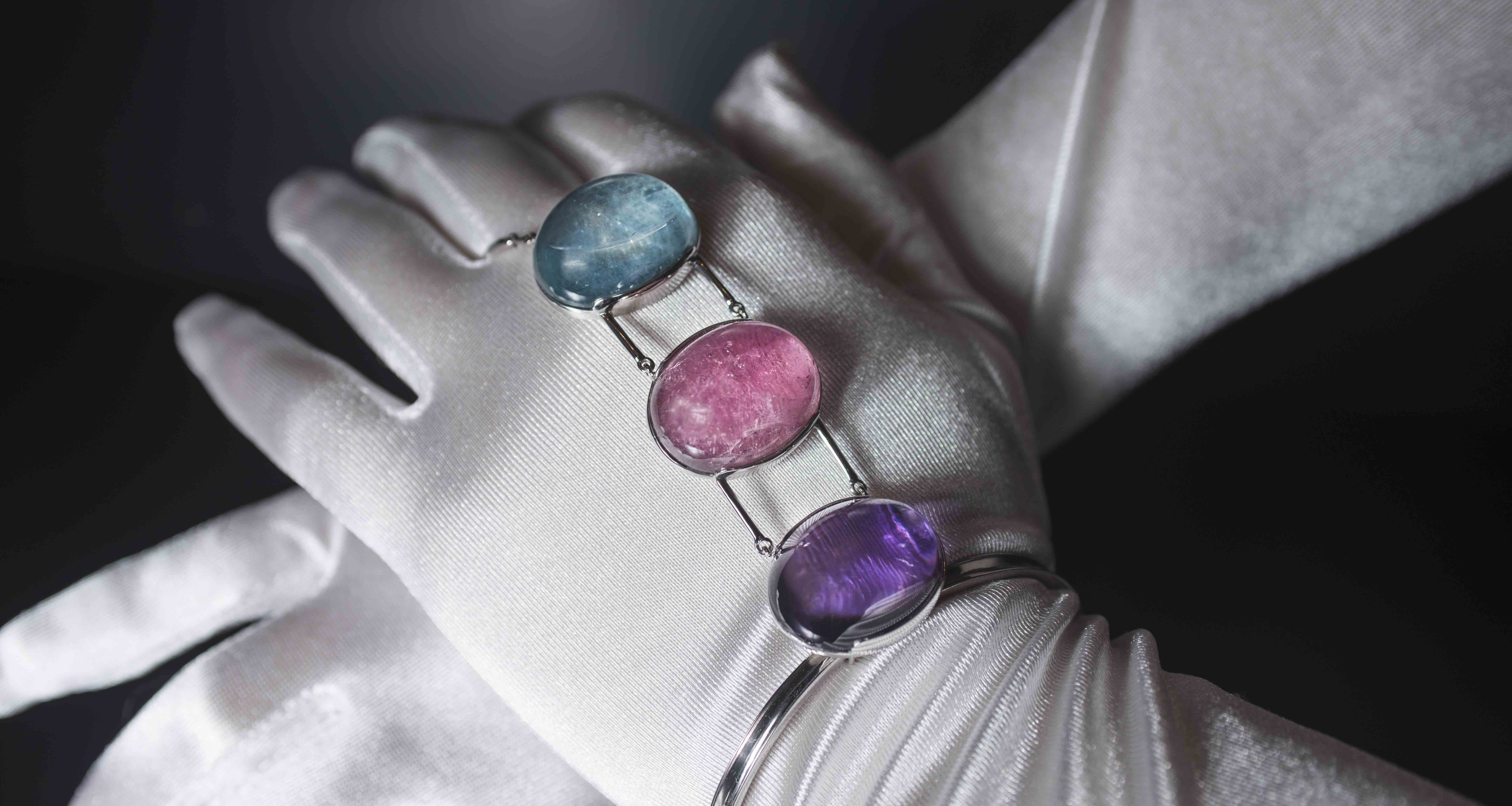 Anello-bracciale in oro bianco uniti da 3 cabochon di quarzo ametista, tormalina rosa e acquamarina.