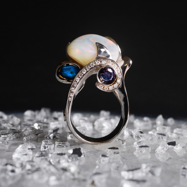 ART.31 - Anello in oro bianco con sublime incontro tra opale arlecchino australiano, apatite gatteggiante e zaffiro metamerico, a raggiungimento di un perfetto equilibrio